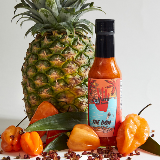 The Don Hot Sauce – Culture Hot Sauce’s original classic! A bold blend of pineapple, habanero, and mustard seed, delivering a bright, exciting flavor with a slow-burning heat. Bottle surrounded by fresh ingredients, showcasing its tropical, tangy, and fiery essence.
