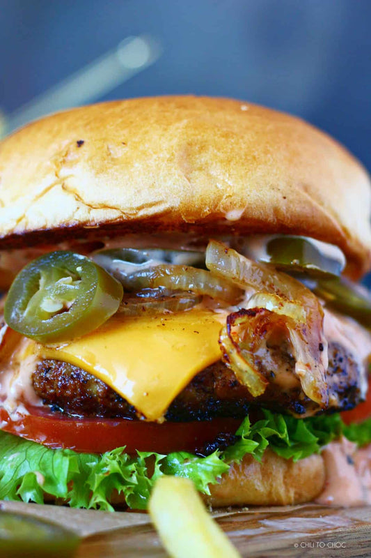 Grilled jalapeño cheddar burger with caramelized onions on a toasted bun, made with fresh ground beef and seasoned with Bar Sauce rub