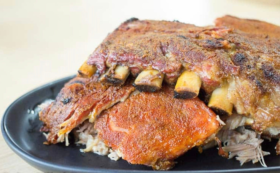 “Oven-baked pork ribs seasoned with award-winning Kitchen Sink Rub, caramelized and fall-off-the-bone tender, baked on a tray and sliced for serving.”