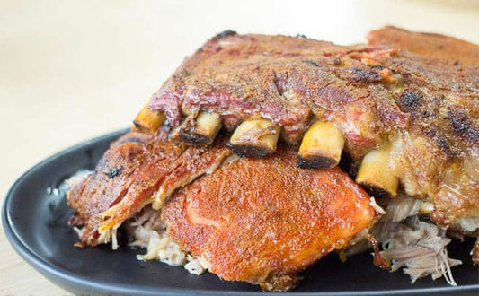 “Oven-baked pork ribs seasoned with award-winning Kitchen Sink Rub, caramelized and fall-off-the-bone tender, baked on a tray and sliced for serving.”