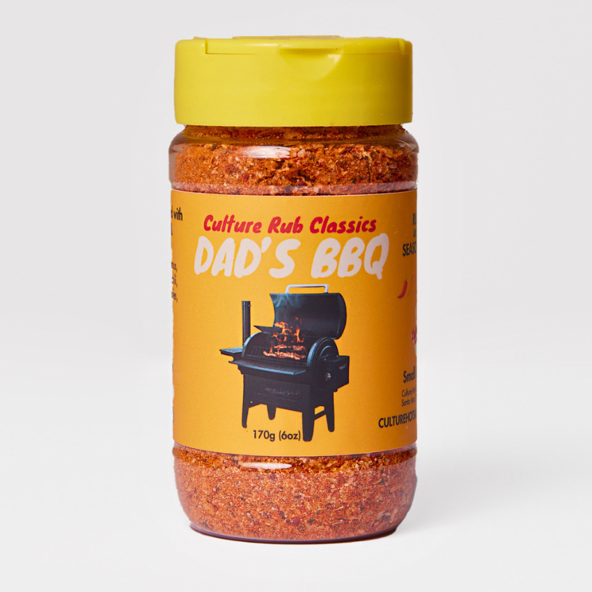 A jar of Culture Rub Classics Dad's BBQ rub salt, featuring a yellow lid and a yellow label with a black grill illustration, set against a light gray background.