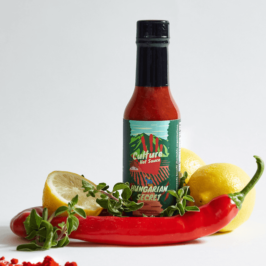 Hungarian secret hot sauce, sweet pepper, red Fresno, the best Hungarian paprika, lemon and herbs surrounding bottle, a best selling hot sauce