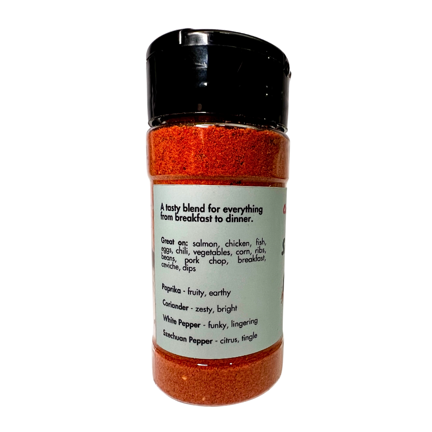 A vibrant, salt-free all-purpose seasoning blend featuring Hungarian paprika, dried garlic, dried onion, coriander seed, white pepper, and Szechuan peppercorn for a bold, zesty, and citrus-forward flavor with a lingering kick. Perfect as a rub or seasoning for salmon, chicken, fish, eggs, chili, vegetables, corn, ribs, beans, pork chops, breakfast, ceviche, and dips. Elevate your dishes with this aromatic, well-balanced spice mix! A tasty blend for everything from breakfast to dinner. Spice jar side image.
